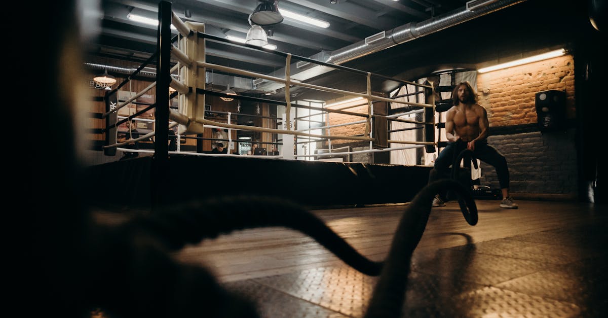 Muscular man engaged in intense rope workout inside industrial gym setting.